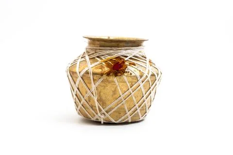 Golden brass pot decorated with string and red ritual powder on a white bac.. Stock Photos
