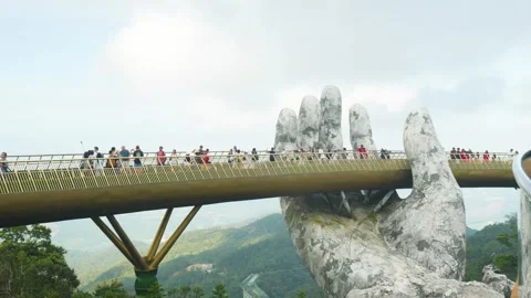 Golden bridge spanning mountain landscape, giant stone hands supporting walkway Stock Footage 315700365