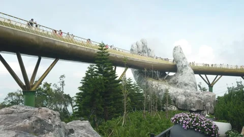 Golden bridge supported by massive stone hands spanning mountainous landscape, Stock Footage 315700011