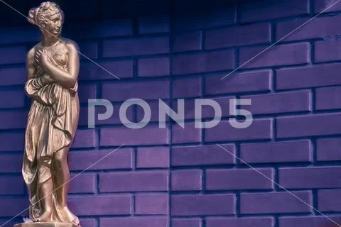 Golden bronze statue of an antique woman and brickwall background for