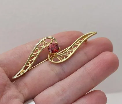Golden brooch with red ruby in hand on white background. Jewelry concept Stock Photos