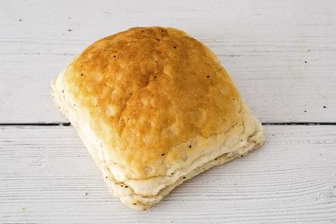 Golden-brown bread roll rests on white wood surface Stock Photos
