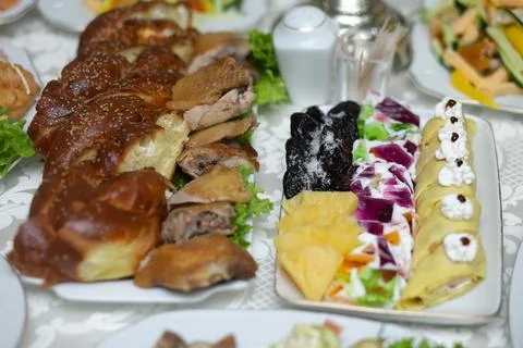 Golden-brown bread rolls sit beside savory meats and colorful salads Foto stock
