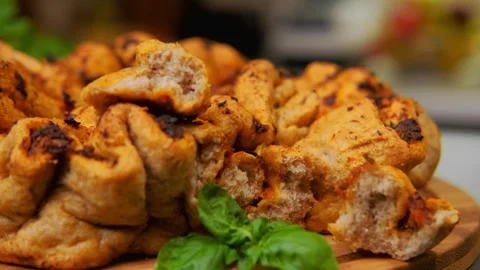 Golden-brown stuffed tomato bread pieces garnished with basil on cutting board Stock Footage 342854658