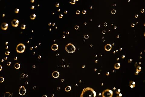 Golden bubbles floating on a black background creating an abstract pattern Stock Photos