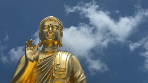 Golden Buddha statue close view with raised hand near chest in symbolic gesture Stockbeeldmateriaal 332723821