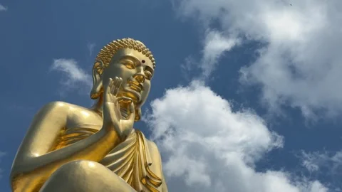 Golden Buddha statue close view with raised hand near face in symbolic mudra aga Stock Footage 339279374