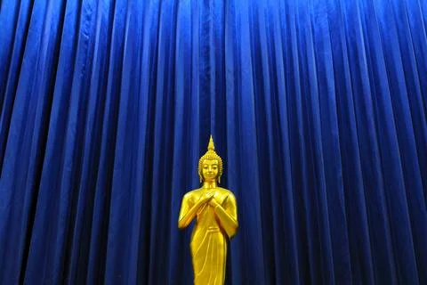 Golden Buddha statue on pattern of blue curtain background. Stock Photos