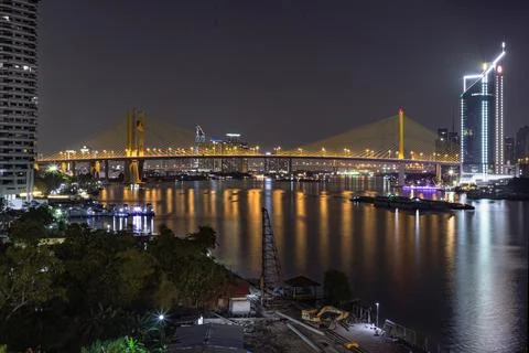 A golden cable-stayed bridge stretches gracefully across a tranquil river, .. Stock Photos
