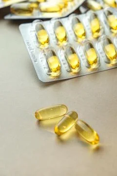 Golden capsules shine on a soft surface near their blister pack Fotos Stock