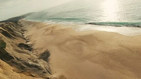 Golden cliffs meet soft waves at a quiet beach Stock Footage 340226865