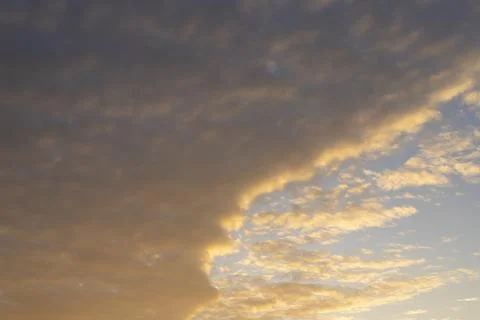 Golden clouds fill a dramatic evening sky. Warm light edges the cloudscape Stock Photos