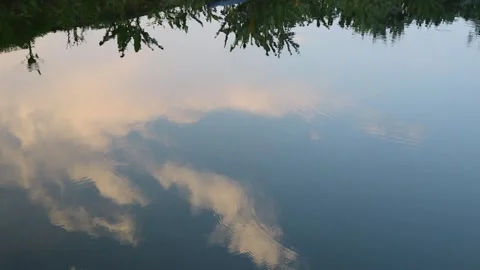 Golden clouds reflected in calm pond with ripples, West Java, Indonesia Stock Footage 342095730