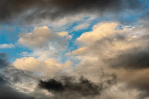  Golden clouds at sunset and thunderclouds floating across sunny blue sky ... Stock Photos