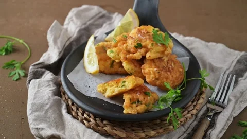 Golden cod fish fritters in a rustic black skillet 動画素材 338365546