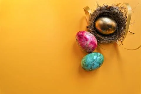 Golden colored easter eggs on yellow background 스톡 사진