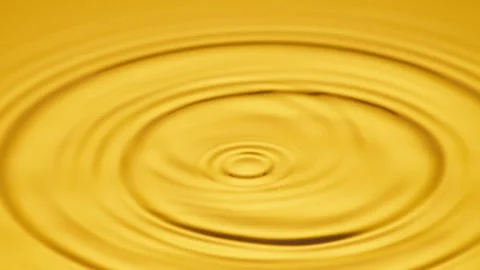 Golden colored Water Drops falling into the water producing waves. Stock Footage 317933543
