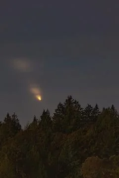 Golden Comet Above Forest with Light Clouds Stock Photos