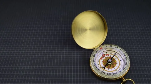 Golden compass open. Needle rotating on a squared black surface. Error magnet Stock Footage 166471027