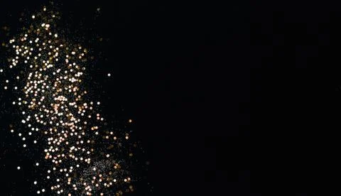 Golden confetti and sparkles on black background. Top view, copy space. Stock Photos