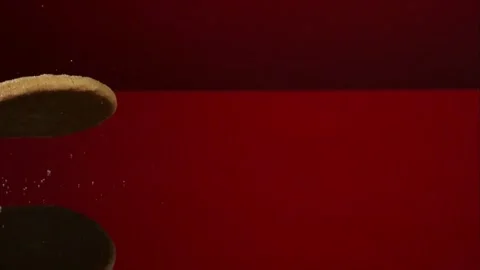 Golden cookies falling and bouncing on a red surface Video stock 327789640