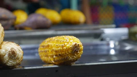 Golden corn is cooked over an open flame, its charred surface promising a Stock Footage 307378529