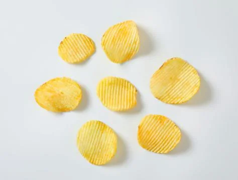 Golden crispy potato chips on plain surface Stock Photos