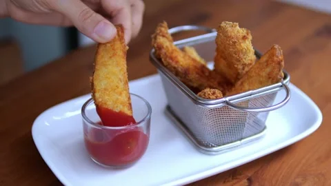 Golden crispy slice of fried potatoes, dipped in tomato sauce. Food in fast food Stock-Footage 197023928