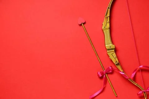 Golden cupid's bow on red background, closeup. Valentine's Day celebration Stock Photos