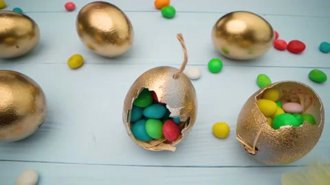 Golden decorative Easter eggs filled with colorful candies on wooden table close 動画素材 146387386