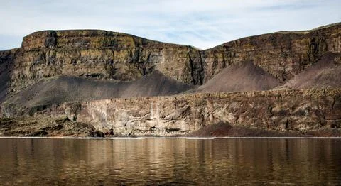 Golden desert ridge eroding with time over a river Stock Photos