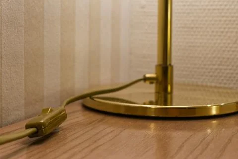Golden desk lamp with inline switch against striped wall Stock Photos