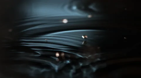 Golden disk-shaped droplets tumbling into dark, ultra-slow motion ripples Stock Footage 59527471