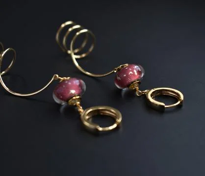 Golden earrings with ruby on a black background close-up Stock Photos