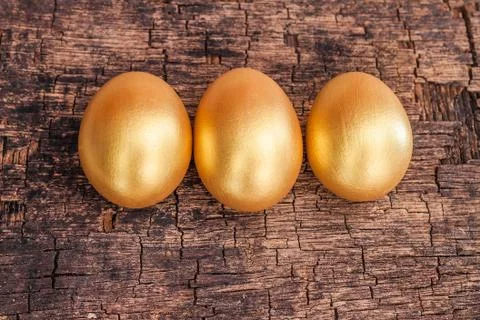 Golden easter egg on brown rough wooden board Stock Photos