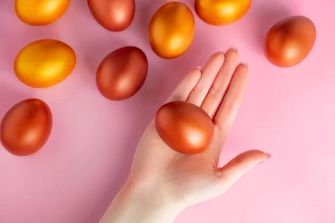 Golden Easter egg in hand on pink background. Happy spring holiday. Stock Photos
