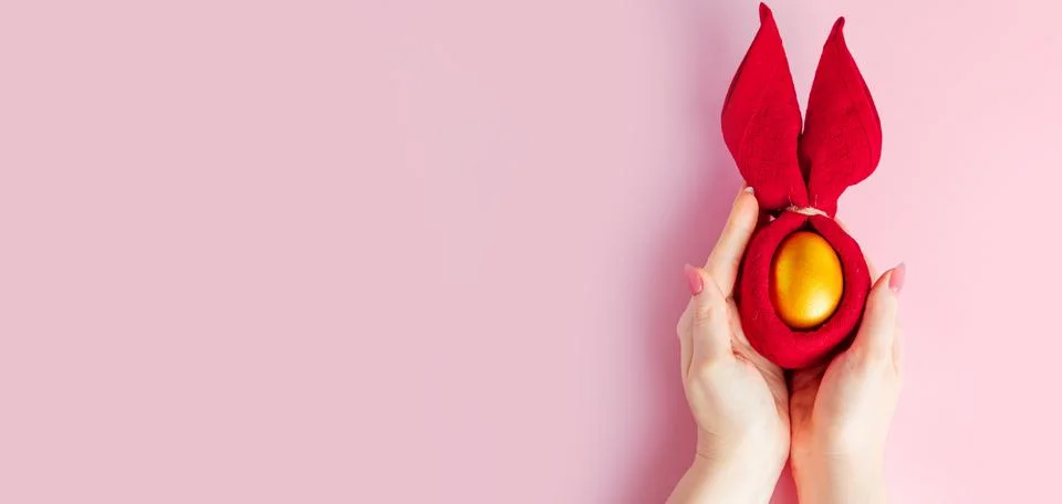 Golden Easter egg in hand on pink background. Happy spring holiday. Foto stock