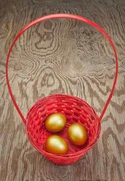 Golden Easter eggs in a red basket. On a wooden texture. Foto stock