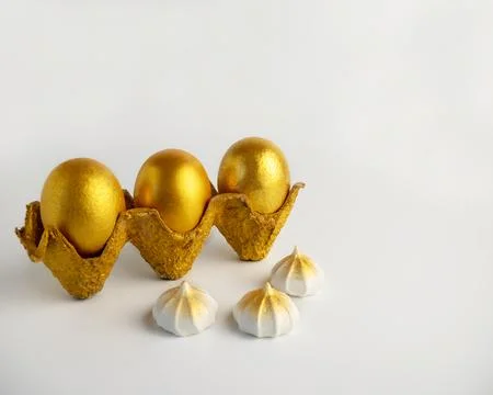 Golden Easter eggs in a textured stand on a white background. Stock Photos