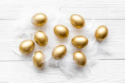Golden Easter eggs with white feather. Top view decoration Stock Photos