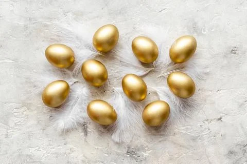 Golden Easter eggs with white feather. Easter decoration, top view Stock Photos