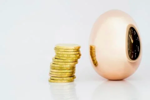 A Golden egg and a stack of shiny coins are reflected in the egg along with t Foto stock