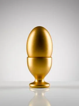 Golden egg in egg cup holder against white background Stock Photos