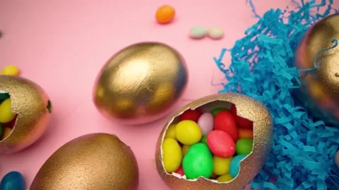 Golden eggs with scattered sweets for Easter on pink background Stock Footage 146388563