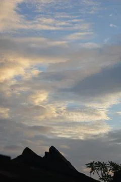 Golden evening clouds over rooftops silhouette with blue sky Stock Photos