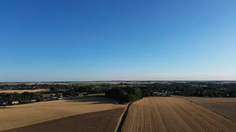 Golden fields stretch beneath a clear blue sky Stock Photos
