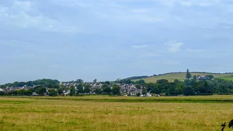 Golden fields stretch wide under soft blue sky to the village of Loans. Stock Photos