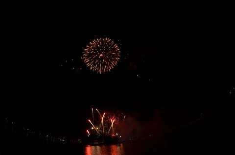 Golden Fireworks Exploding in Night Sky over River Festival Celebration Stock Photos
