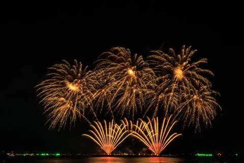 Golden Fireworks Exploding Over Calm Sea At Night 스톡 사진