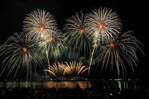 Golden Fireworks Exploding Over Dark Horizon With Silhouette Crowd Watching.. Stock Photos